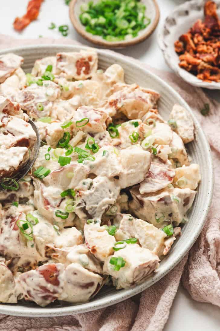 Potato and bacon salad in a white bowl.
