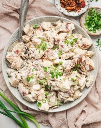A white bowl filled with potato salad with bacon.