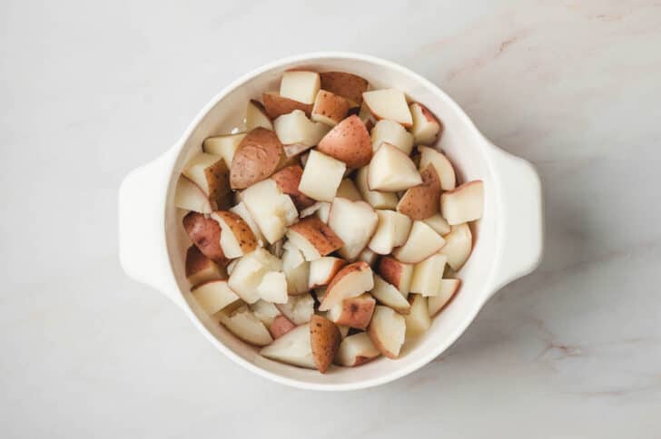 Cooked chopped redskin potatoes in a colander.
