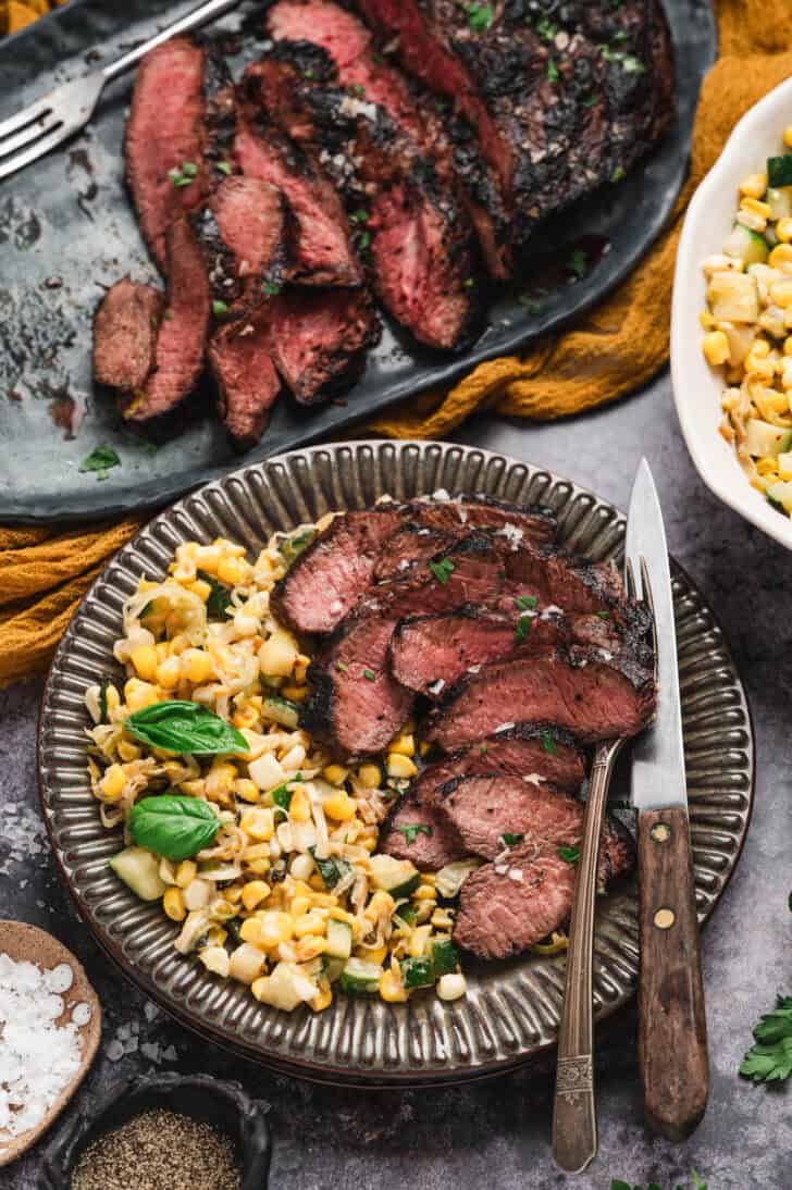 A plate filled with corn salad and thinly sliced flat iron steak.
