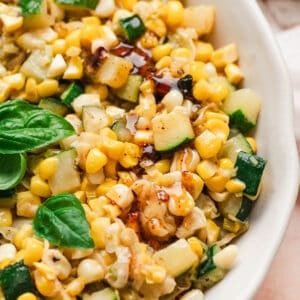 A shallow white bowl filled with a zucchini and corn recipe.