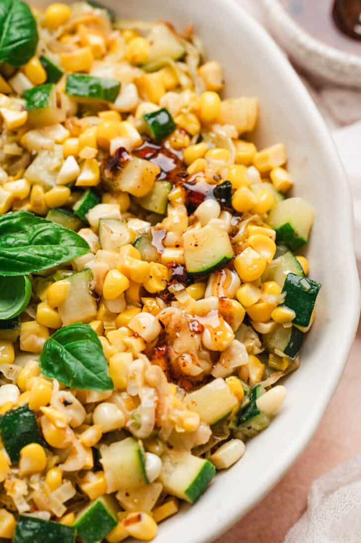 A shallow white bowl filled with a zucchini and corn recipe.