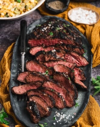 Marinated flat iron steak, cooked and thinly sliced, on a platter.
