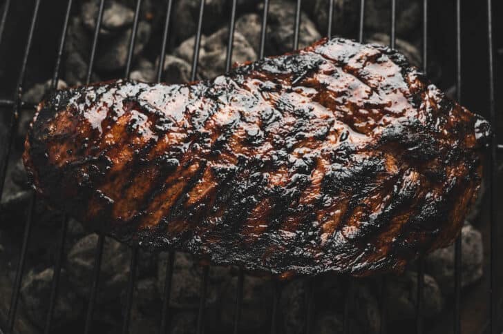 A marinated flat iron steak being cooked on a grill.