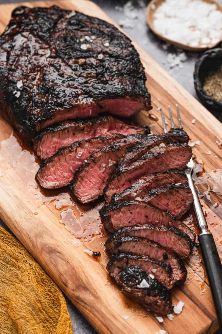 A thinly sliced flat iron steak on a cutting board.