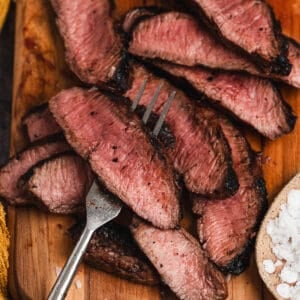 A fork skewering a piece of beef that has been cooked with a flat iron steak marinade on it.