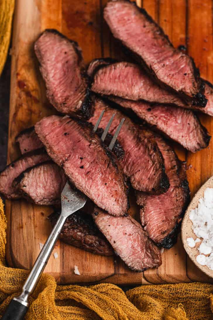 A fork skewering a piece of beef that has been cooked with a flat iron steak marinade on it.
