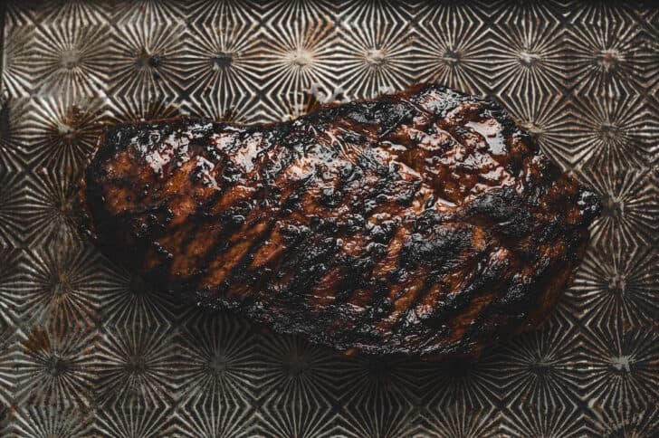 A cooked, marinated flat iron steak resting on a baking pan.