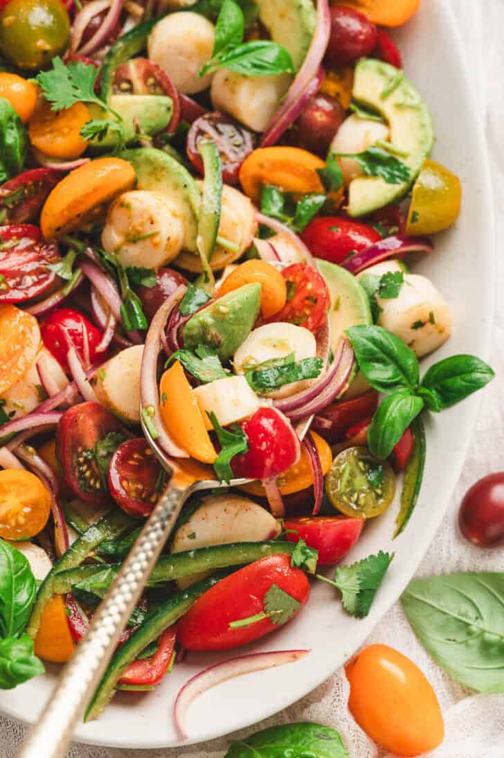 Palmito salad spoonful with hearts of palm, avocado, cherry tomatoes, red onion, basil and cilantro.