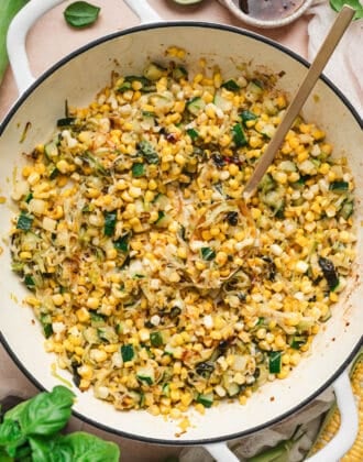 A white skillet with handles filled with a zucchini and corn recipe.