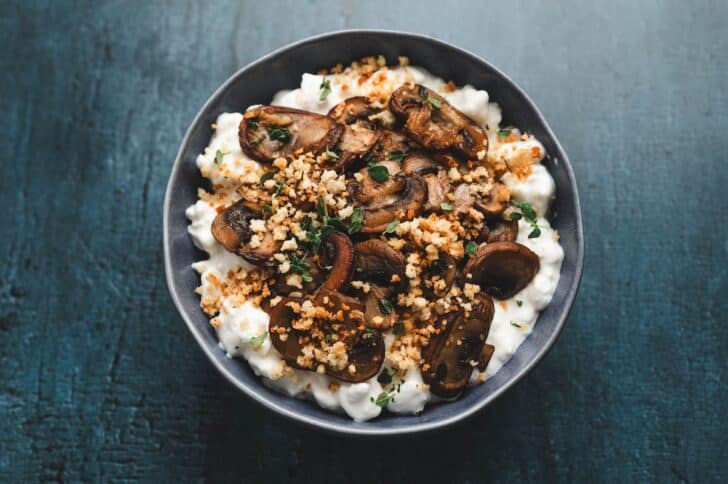 Overhead view of a roasted mushroom and thyme cottage cheese bowl, topped with toasted panko breadcrumbs and fresh thyme leaves.