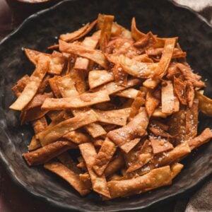 Close-up of a bowl filled with tortilla strips for salad, fried until golden and sprinkled with flaky sea salt.