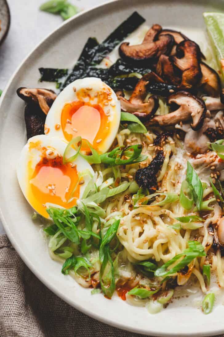 Close-up of creamy miso ramen with a jammy soft-boiled egg, crispy nori strips, and sautéed mushrooms over noodles