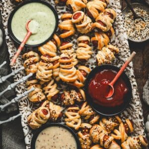 Close crop of a platter of mummy pigs in a blanket surrounded by dipping sauces and Halloween decor