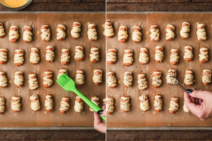 Process shots of egg wash being brushed onto wrapped sausages, then everything bagel seasoning sprinkled over unbaked mummy pigs in a blanket