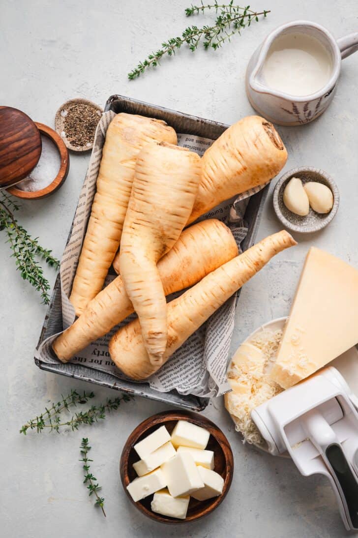 ngredients laid out, including whole peeled parsnips, heavy cream, cubed butter, grated Parmesan cheese, garlic cloves, and fresh thyme sprigs
