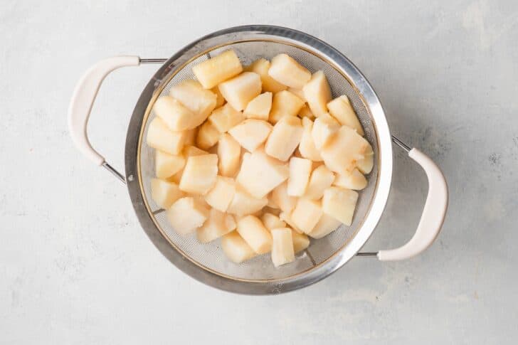 Cooked parsnip chunks draining in a colander