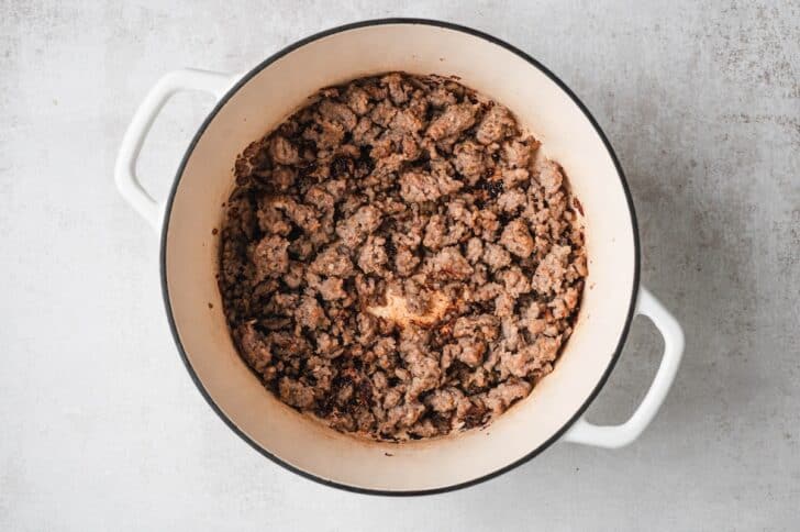 Process shot of ground Italian sausage browned and crumbled in a Dutch oven